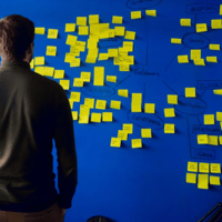 Man standing in front of a blue strategy board with writing and post it notes