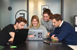 4 person business team working together around 1 computer