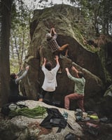 Team helping each other climb a rock