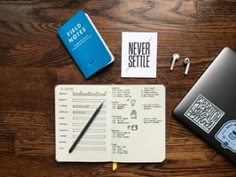 Desk full of employee tools and sign that says never settle