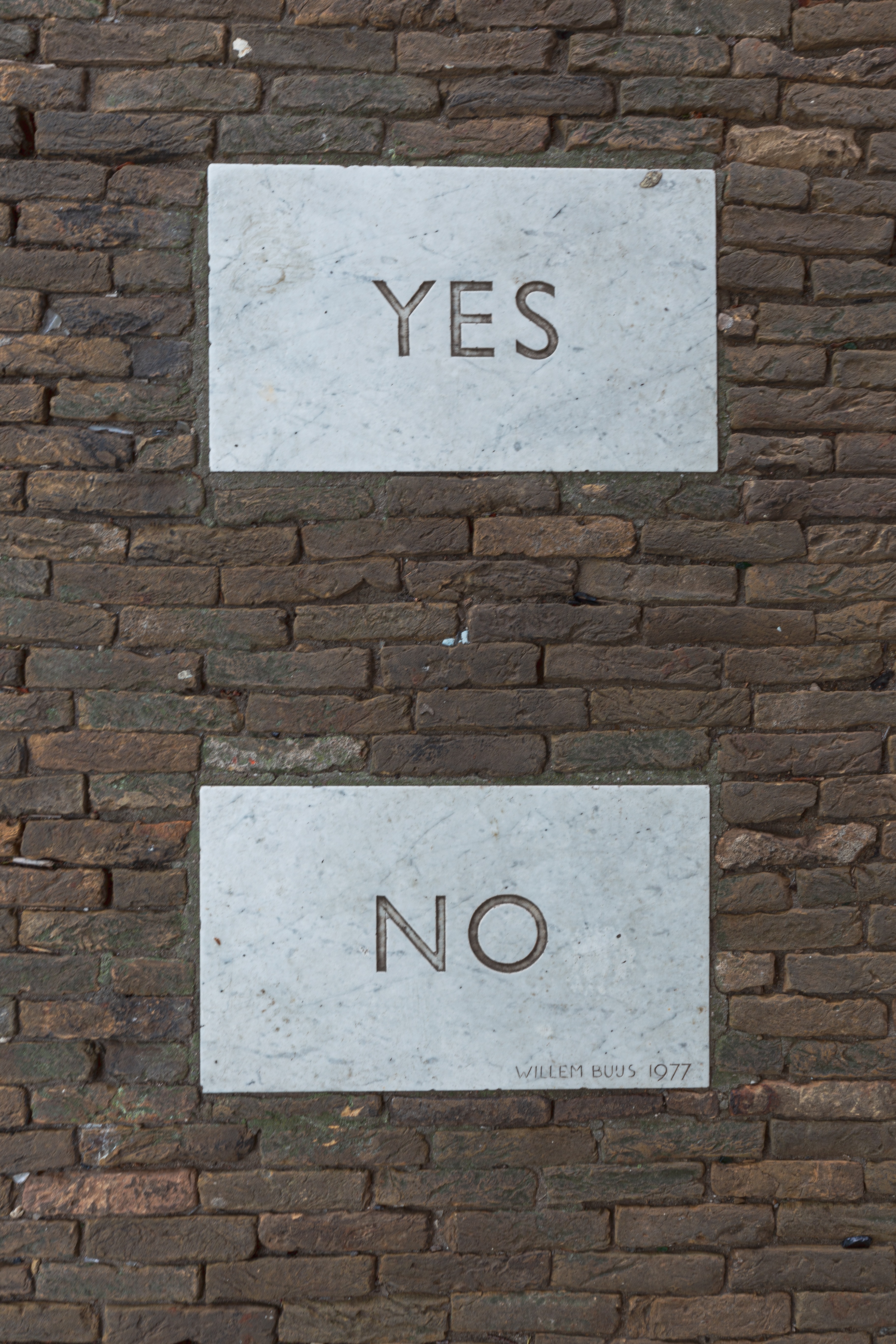 Brick wall with a Yes and No sign in vertical order